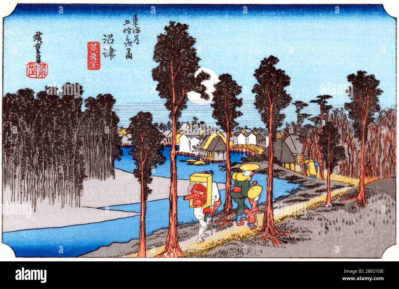 Giappone: "Stazione dodici: Numazu al crepuscolo". Ukiyo-e xilografia della serie '53 stazioni della strada Tôkaidô' di Utagawa Hiroshige (1797-1858), 1834 circa. Numazu: Viaggiatori che camminano lungo la riva del fiume, fiancheggiata da alberi, verso il villaggio che precede, sotto un'enorme luna piena in un cielo blu profondo, uno di loro porta sulla schiena una grande maschera Tengu, il segno di un pellegrino al santuario shintoista di Kompira sull'isola di Shikoku. Foresta scura di alberi su un'altra riva del fiume. Foto Stock