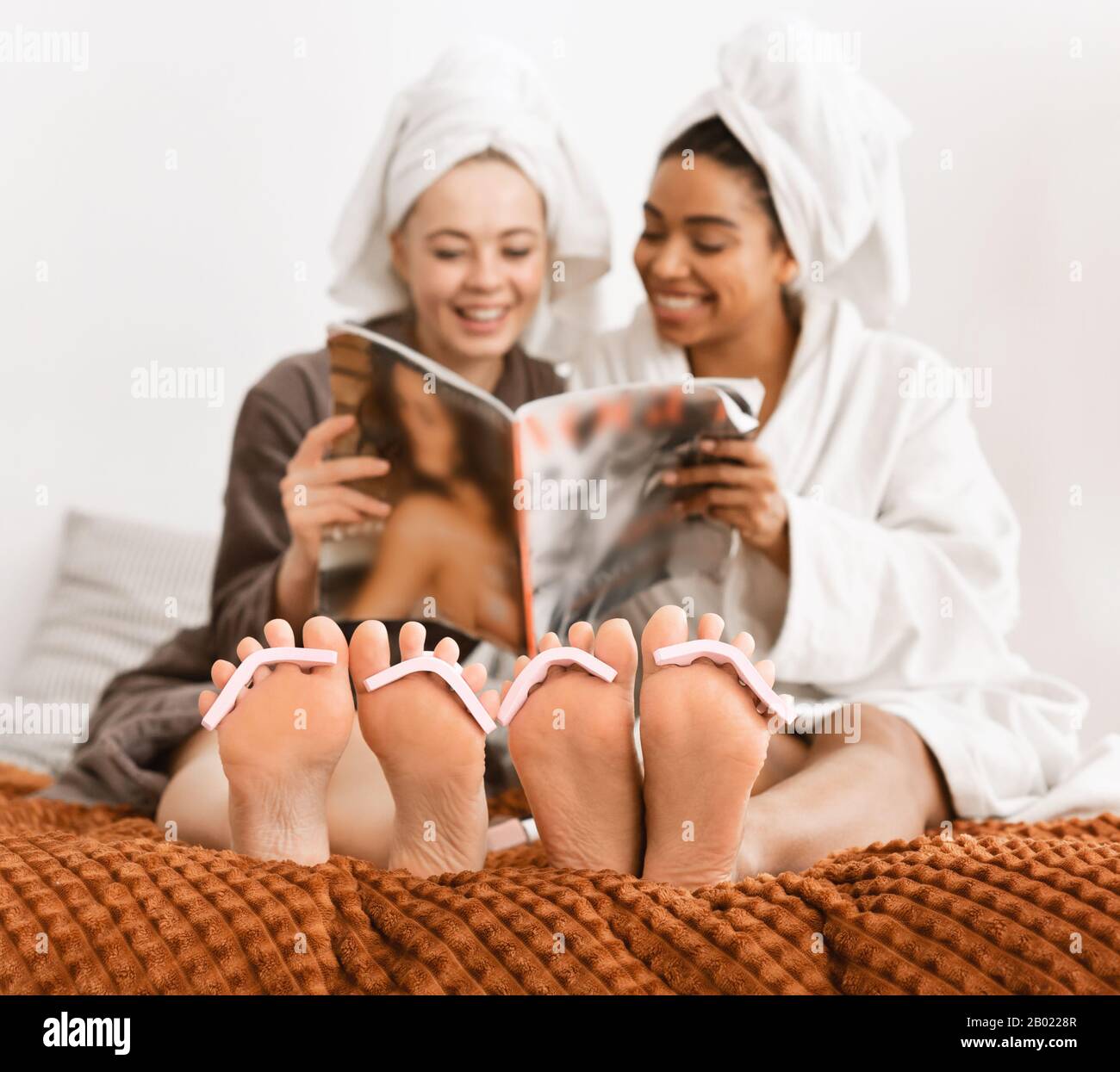 Girlfriends fare pedicure a casa, lettura rivista Foto Stock