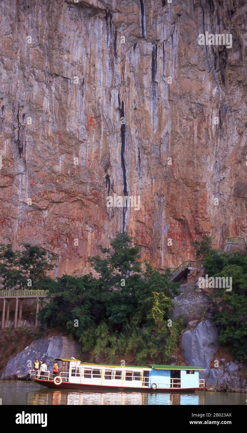 Cina: Barca sotto i dipinti della scogliera di Huashan (Huashan Bihua), fiume Zuo (Zuo Jiang), riserva naturale di Longrui, provincia del Guangxi. I dipinti della scogliera Huashan si trovano lungo il fiume Zuo nella provincia del Guangxi e si ritiene che abbiano circa 2000 anni. Ci sono 60 dipinti in tutto con un totale di 1.770 figure umane. I dipinti furono eseguiti dal popolo Luoyue, antenati della locale minoranza Zhuang. Lo Zuojiang o fiume Zuo (letteralmente "fiume sinistro") è un fiume della provincia del Guangxi, nella Cina meridionale. Sfocia nel Mar Cinese meridionale. Foto Stock