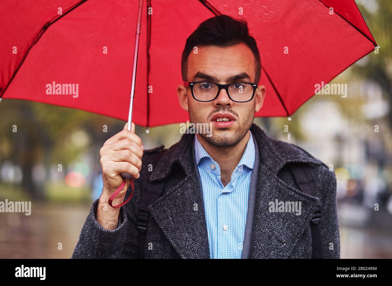 l'uomo d'affari depresso va sotto la pioggia con l'ombrello Foto Stock