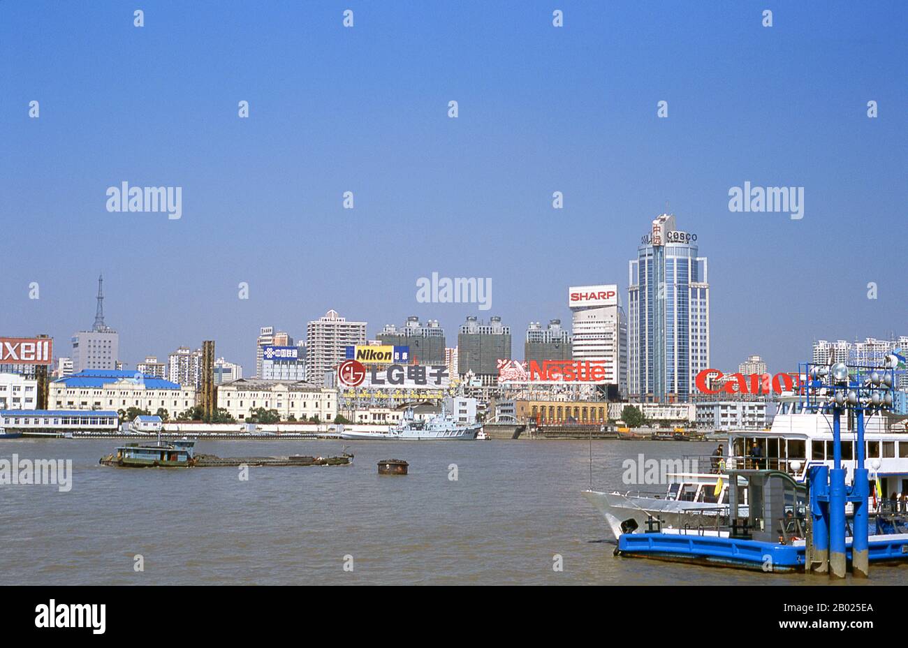 Cina: Traffico commerciale sul fiume Huangpu, Shanghai, 2000. Shanghai iniziò la sua vita come villaggio di pescatori, e più tardi come porto che riceveva merci trasportate lungo il fiume Yangzi. Dal 1842 in poi, dopo la prima guerra dell'oppio, i britannici aprirono una "concessione" a Shanghai, dove i trafficanti di droga e altri commercianti potevano operare indisturbati. Francesi, italiani, tedeschi, americani e giapponesi seguirono tutti. Negli anni '1920 e '1930, Shanghai era una città boom e una parola d'ordine internazionale per la dissipazione. Quando i comunisti conquistarono il potere nel 1949, trasformarono Shanghai in un modello della rivoluzione. Foto Stock