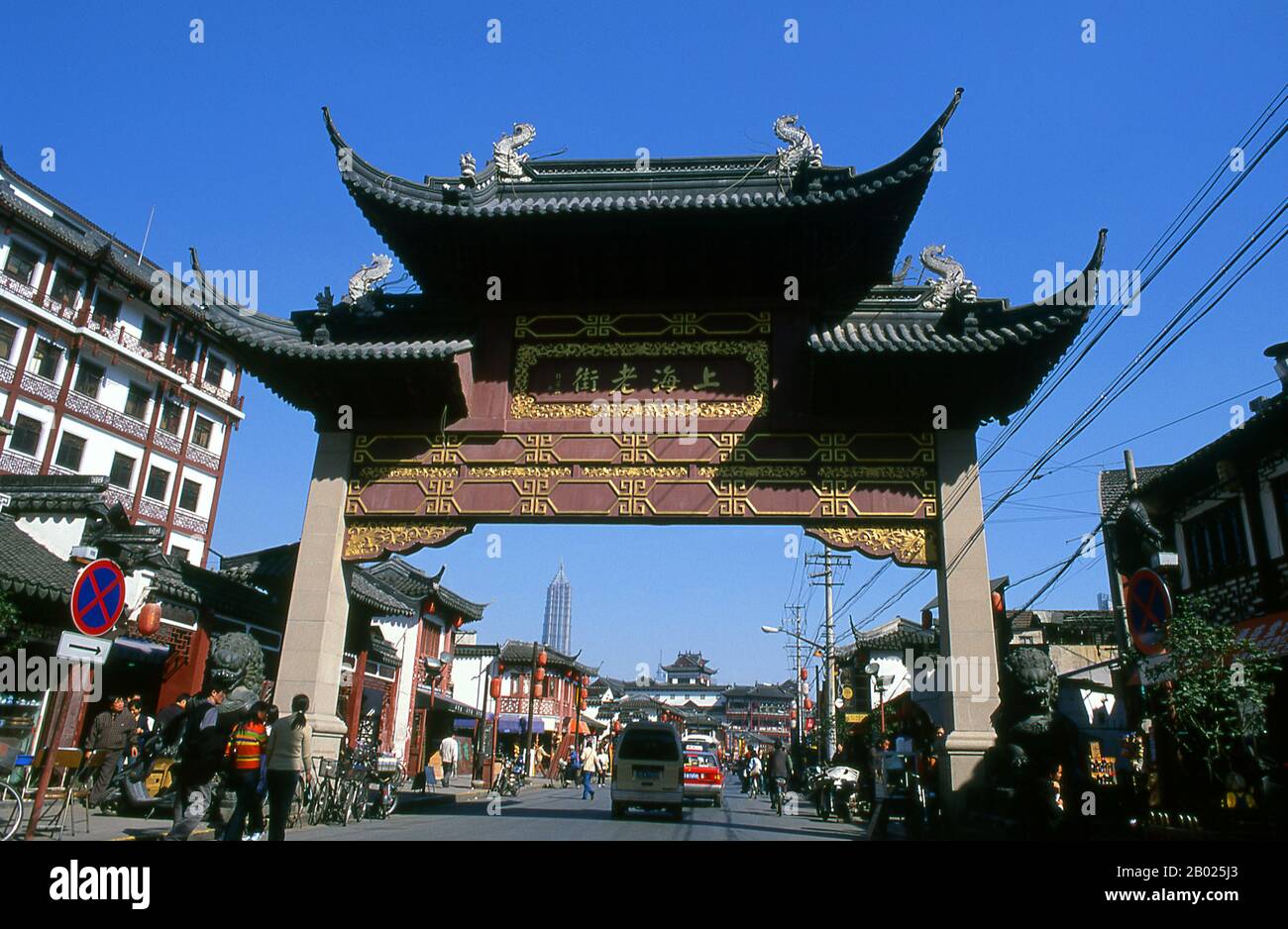 Cina: Un'elaborata porta paifang che porta a Fangbang Lu con la Torre Jin Mao sullo sfondo (Pudong), Nanshi o l'area della città Vecchia, Shanghai. Shanghai iniziò la sua vita come villaggio di pescatori, e più tardi come porto che riceveva merci trasportate lungo il fiume Yangzi. Dal 1842 in poi, dopo la prima guerra dell'oppio, i britannici aprirono una "concessione" a Shanghai, dove i trafficanti di droga e altri commercianti potevano operare indisturbati. Francesi, italiani, tedeschi, americani e giapponesi seguirono tutti. Negli anni '1920 e '1930, Shanghai era una città boom e una parola d'ordine internazionale per la dissipazione. Foto Stock