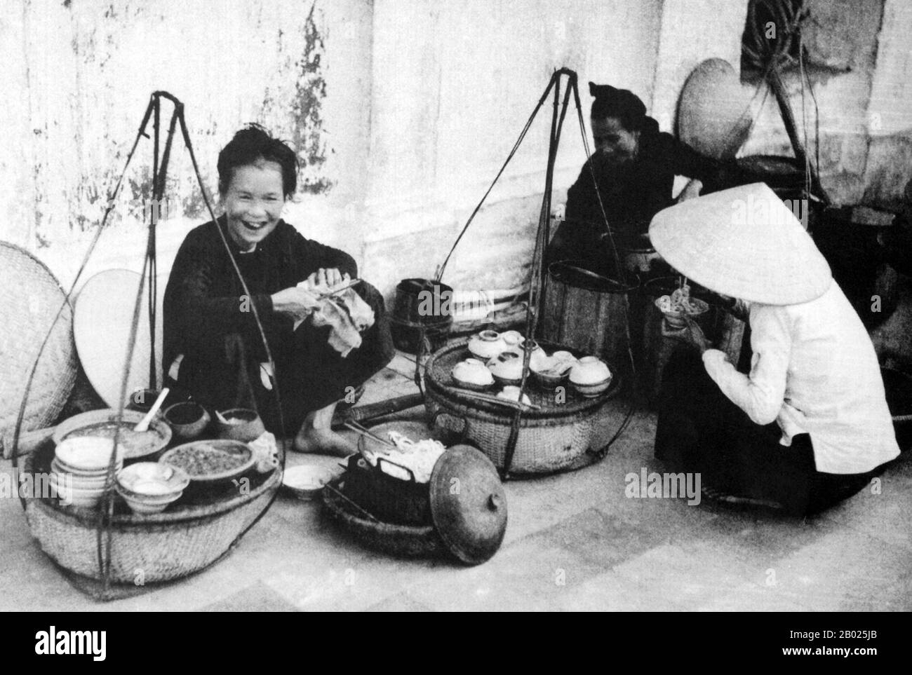 Vietnam: Un venditore di noodle Cao Lau, una specialità Hoi An e Quang Nam, Hoi An, 1950. La piccola ma storica città di ho An si trova sul fiume Thu Bon, 30 km a sud di Danang. Durante il tempo dei signori Nguyen (1558-1777) e anche sotto i primi imperatori Nguyen, Hoi An - allora conosciuto come Faifo - era un porto importante, visitato regolarmente da navi provenienti dall'Europa e da tutto l'Oriente. Verso la fine del XIX secolo, l'insabbiamento del fiume Thu Bon e lo sviluppo della vicina Danang si erano combinati per rendere Hoi An un'acqua arretrata. Foto Stock