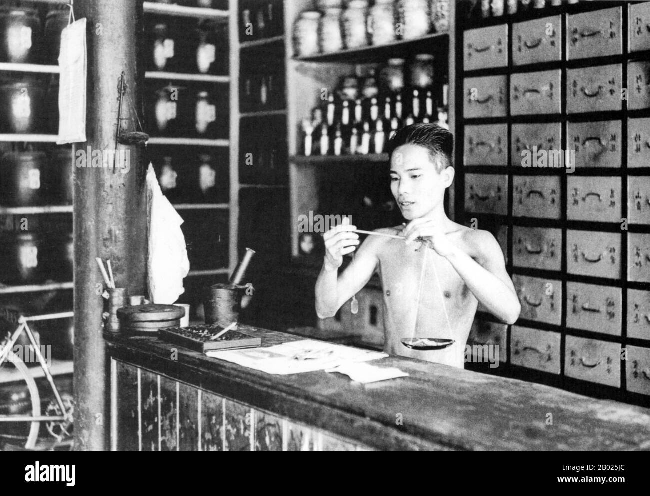 Vietnam: Pesare i medicinali in un negozio di medicina cinese, Hoi An, 1950. La piccola ma storica città di ho An si trova sul fiume Thu Bon, 30 km a sud di Danang. Durante il tempo dei signori Nguyen (1558-1777) e anche sotto i primi imperatori Nguyen, Hoi An - allora conosciuto come Faifo - era un porto importante, visitato regolarmente da navi provenienti dall'Europa e da tutto l'Oriente. Verso la fine del XIX secolo, l'insabbiamento del fiume Thu Bon e lo sviluppo della vicina Danang si erano combinati per rendere Hoi An un'acqua arretrata. Foto Stock