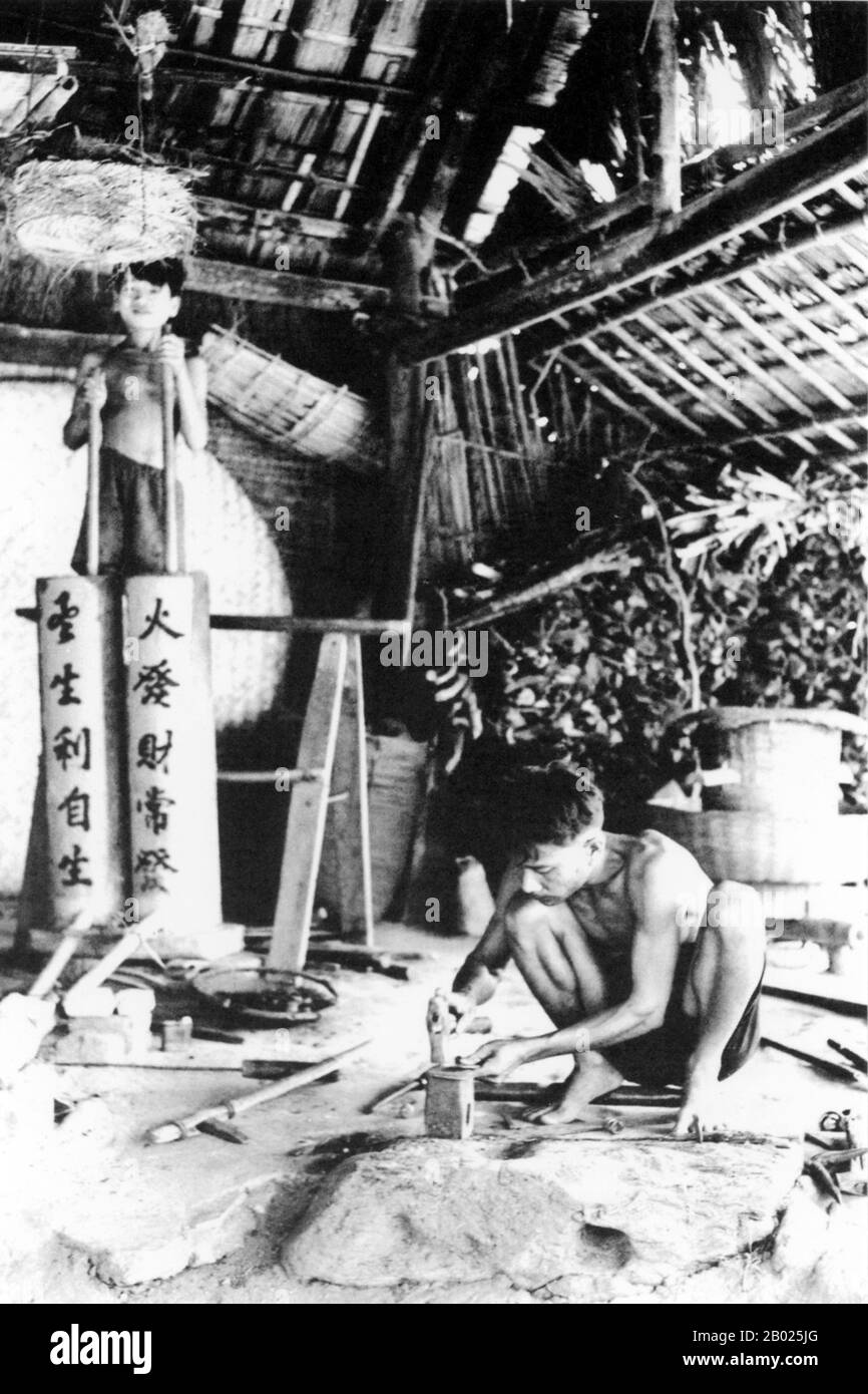 Vietnam: Un fabbro con il suo assistente che usa mantici in stile cinese a Hoi An, 1950. La piccola ma storica città di ho An si trova sul fiume Thu Bon, 30 km a sud di Danang. Durante il tempo dei signori Nguyen (1558-1777) e anche sotto i primi imperatori Nguyen, Hoi An - allora conosciuto come Faifo - era un porto importante, visitato regolarmente da navi provenienti dall'Europa e da tutto l'Oriente. Verso la fine del XIX secolo, l'insabbiamento del fiume Thu Bon e lo sviluppo della vicina Danang si erano combinati per rendere Hoi An un'acqua arretrata. Foto Stock