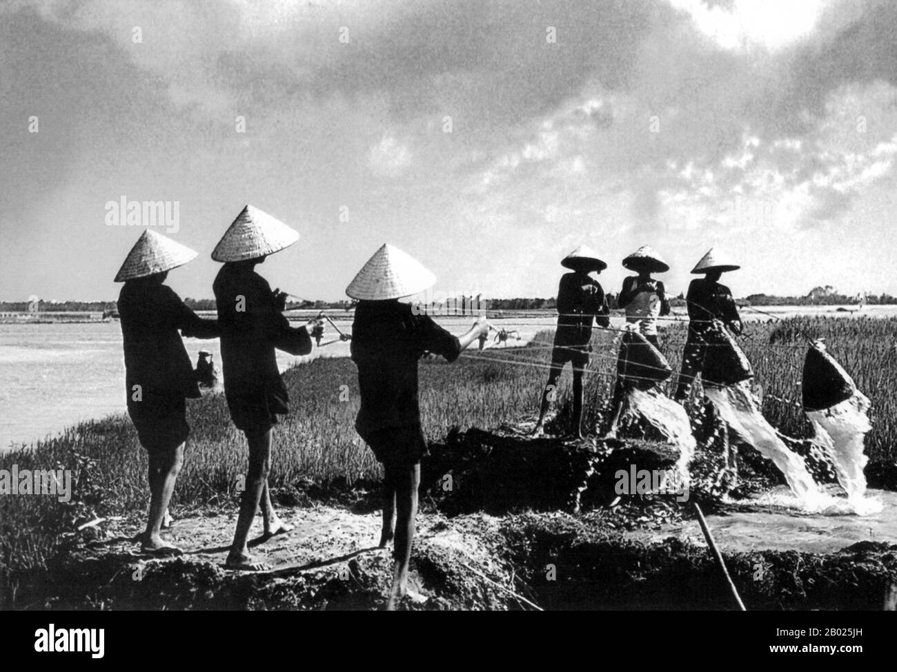 Vietnam: Agricoltori che irrigano campi di riso vicino a Hoi An, 1950. La piccola ma storica città di ho An si trova sul fiume Thu Bon, 30 km a sud di Danang. Durante il tempo dei signori Nguyen (1558-1777) e anche sotto i primi imperatori Nguyen, Hoi An - allora conosciuto come Faifo - era un porto importante, visitato regolarmente da navi provenienti dall'Europa e da tutto l'Oriente. Verso la fine del XIX secolo, l'insabbiamento del fiume Thu Bon e lo sviluppo della vicina Danang si erano combinati per rendere Hoi An un'acqua arretrata. Foto Stock