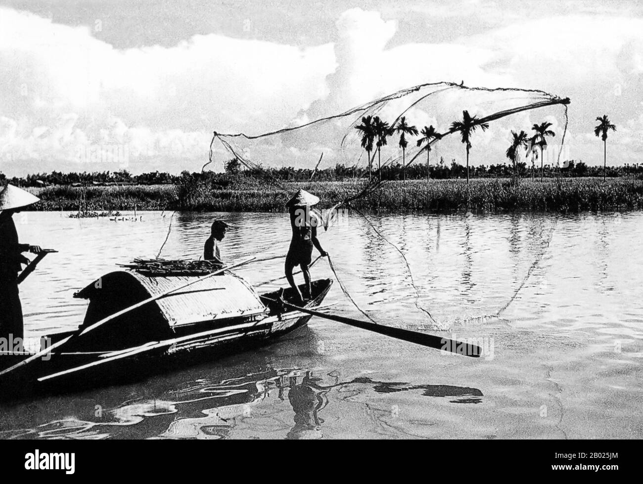 Vietnam: Un pescatore getta la sua rete sul fiume Thu Bon vicino a Hoi An, 1950. La piccola ma storica città di ho An si trova sul fiume Thu Bon, 30 km a sud di Danang. Durante il tempo dei signori Nguyen (1558-1777) e anche sotto i primi imperatori Nguyen, Hoi An - allora conosciuto come Faifo - era un porto importante, visitato regolarmente da navi provenienti dall'Europa e da tutto l'Oriente. Verso la fine del XIX secolo, l'insabbiamento del fiume Thu Bon e lo sviluppo della vicina Danang si erano combinati per rendere Hoi An un'acqua arretrata. Foto Stock