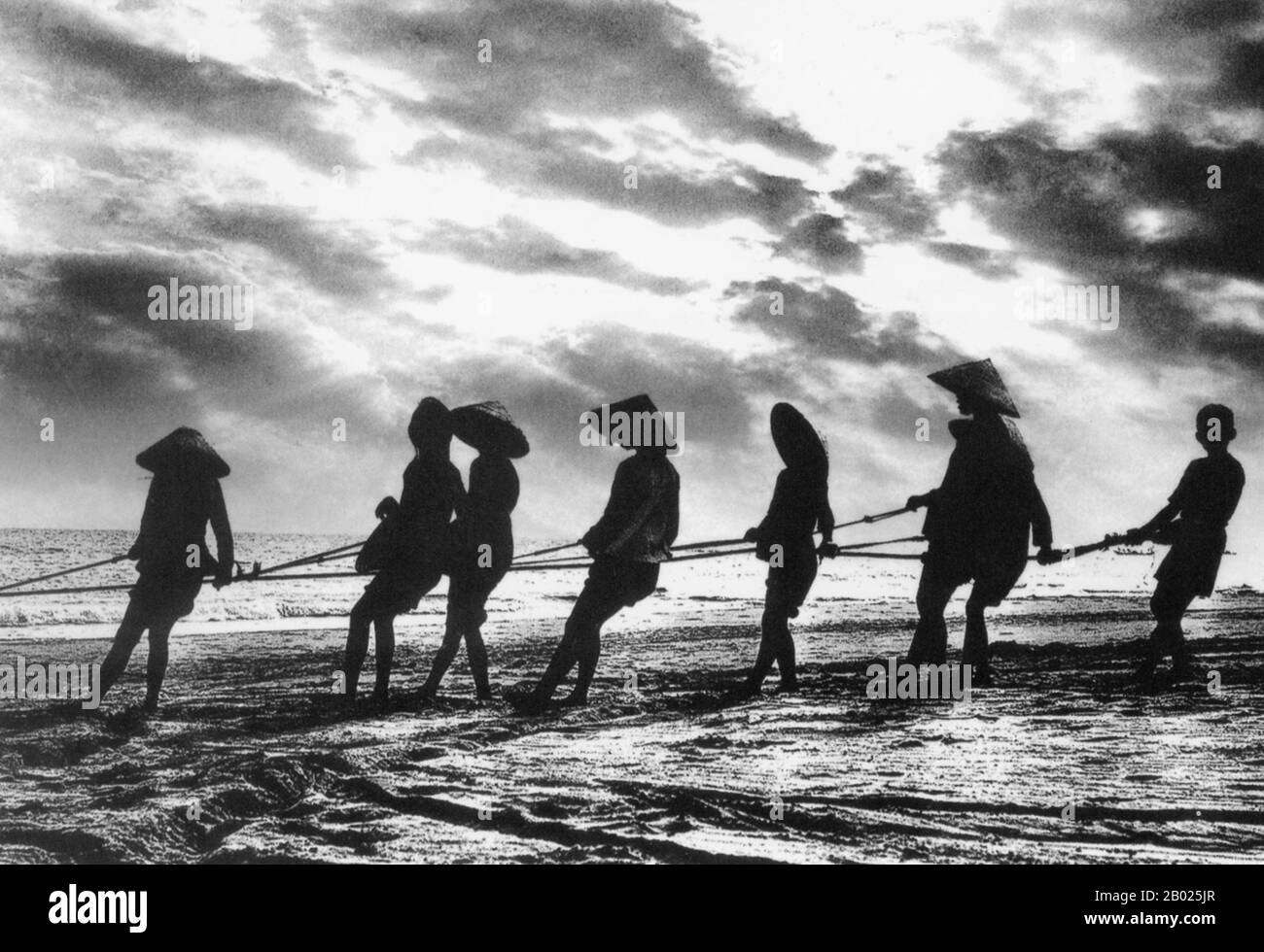 Vietnam: Tirare le reti da pesca sulla spiaggia, Hoi An, 1950. La piccola ma storica città di ho An si trova sul fiume Thu Bon, 30 km a sud di Danang. Durante il tempo dei signori Nguyen (1558-1777) e anche sotto i primi imperatori Nguyen, Hoi An - allora conosciuto come Faifo - era un porto importante, visitato regolarmente da navi provenienti dall'Europa e da tutto l'Oriente. Verso la fine del XIX secolo, l'insabbiamento del fiume Thu Bon e lo sviluppo della vicina Danang si erano combinati per rendere Hoi An un'acqua arretrata. Foto Stock