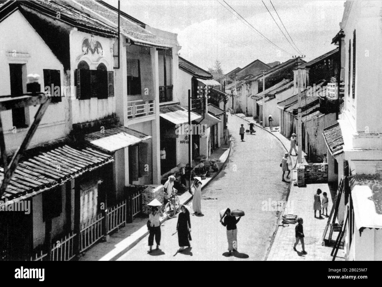 Vietnam: Tran Phu Street, Hoi An, c. 1950. La piccola ma storica cittadina di Hoi An si trova sul fiume Thu Bon, 30 km a sud di Danang. Durante il tempo dei signori Nguyen (1558-1777) e anche sotto i primi imperatori Nguyen, Hoi An - allora conosciuto come Faifo - era un porto importante, visitato regolarmente da navi provenienti dall'Europa e da tutto l'Oriente. Verso la fine del XIX secolo, l'insabbiamento del fiume Thu Bon e lo sviluppo della vicina Danang si erano combinati per rendere Hoi An un'acqua arretrata. Questa oscurità salvò la città da seri combattimenti durante le guerre con la Francia e gli Stati Uniti. Foto Stock