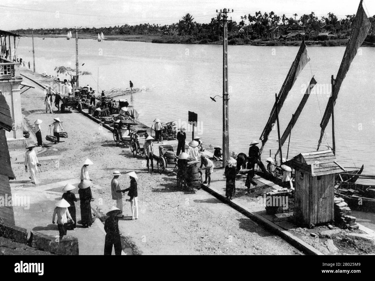 Vietnam: Autisti e venditori di cicloturisti presso il fiume Thu Bon nel centro di Hoi An, c. 1950. La piccola ma storica cittadina di Hoi An si trova sul fiume Thu Bon, 30 km a sud di Danang. Durante il tempo dei signori Nguyen (1558-1777) e anche sotto i primi imperatori Nguyen, Hoi An - allora conosciuto come Faifo - era un porto importante, visitato regolarmente da navi provenienti dall'Europa e da tutto l'Oriente. Verso la fine del XIX secolo, l'insabbiamento del fiume Thu Bon e lo sviluppo della vicina Danang si erano combinati per rendere Hoi An un'acqua arretrata. Foto Stock