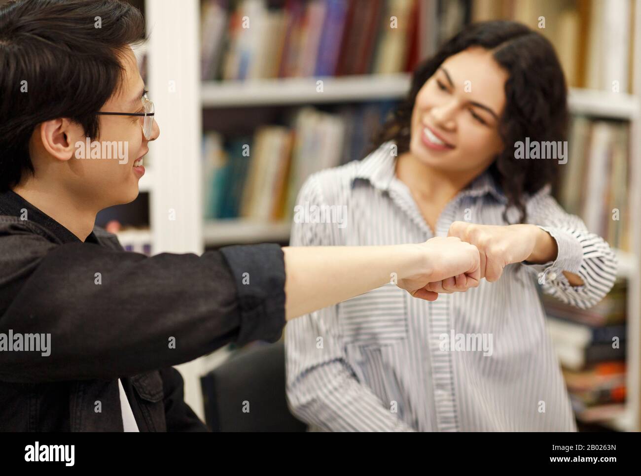 Coppia allegra che fa un gesto frettoloso nella biblioteca Foto Stock