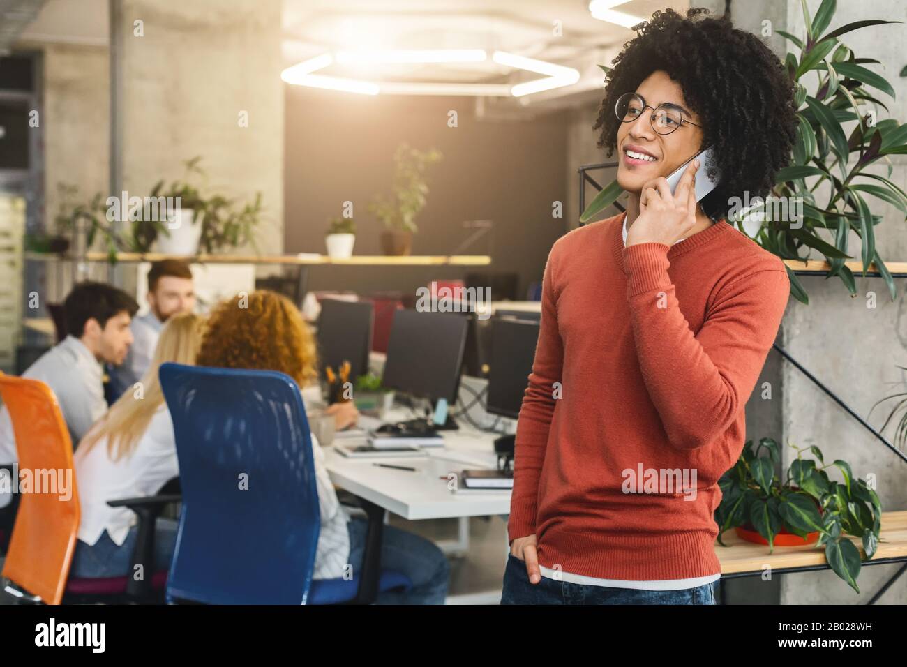 Sorridente afro che ha conversato al telefono in ufficio Foto Stock