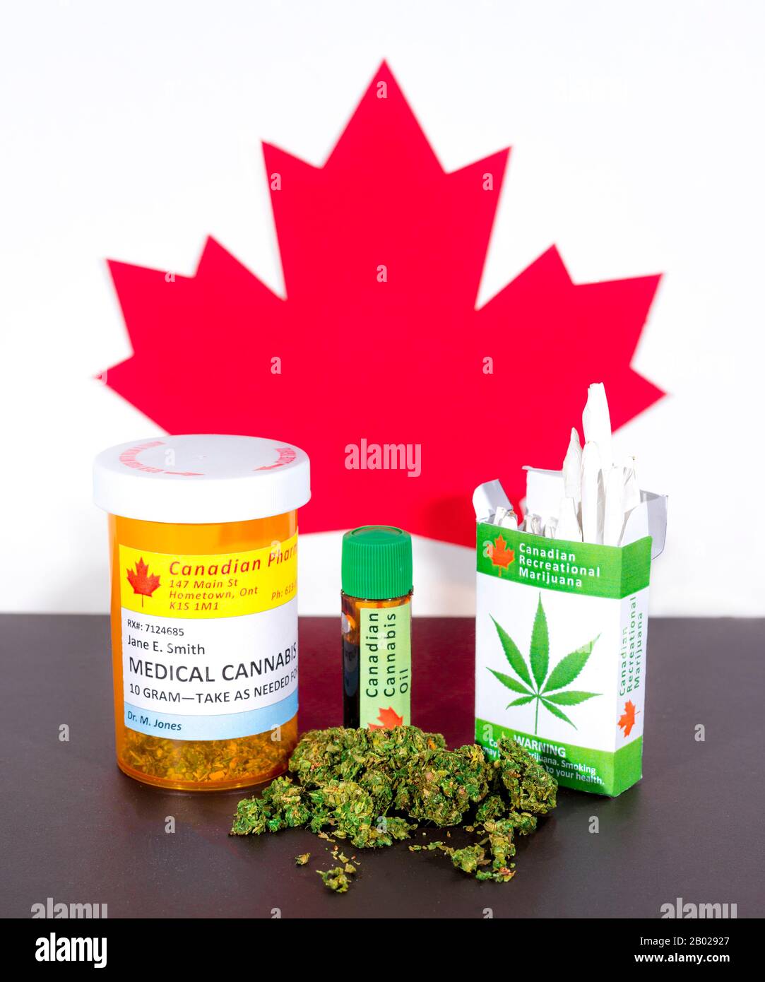 Cannabis in Canada. Cannabis medica, olio di cannabis, boccioli, e un pacchetto di sigarette di cannabis su un tavolo, con una foglia di acero canadese dietro. Foto Stock
