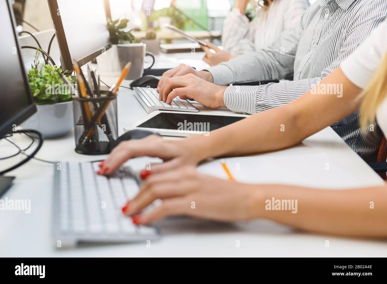 Taglio corto di persone che digitano a mano sulla tastiera, utilizzando un tablet digitale Foto Stock
