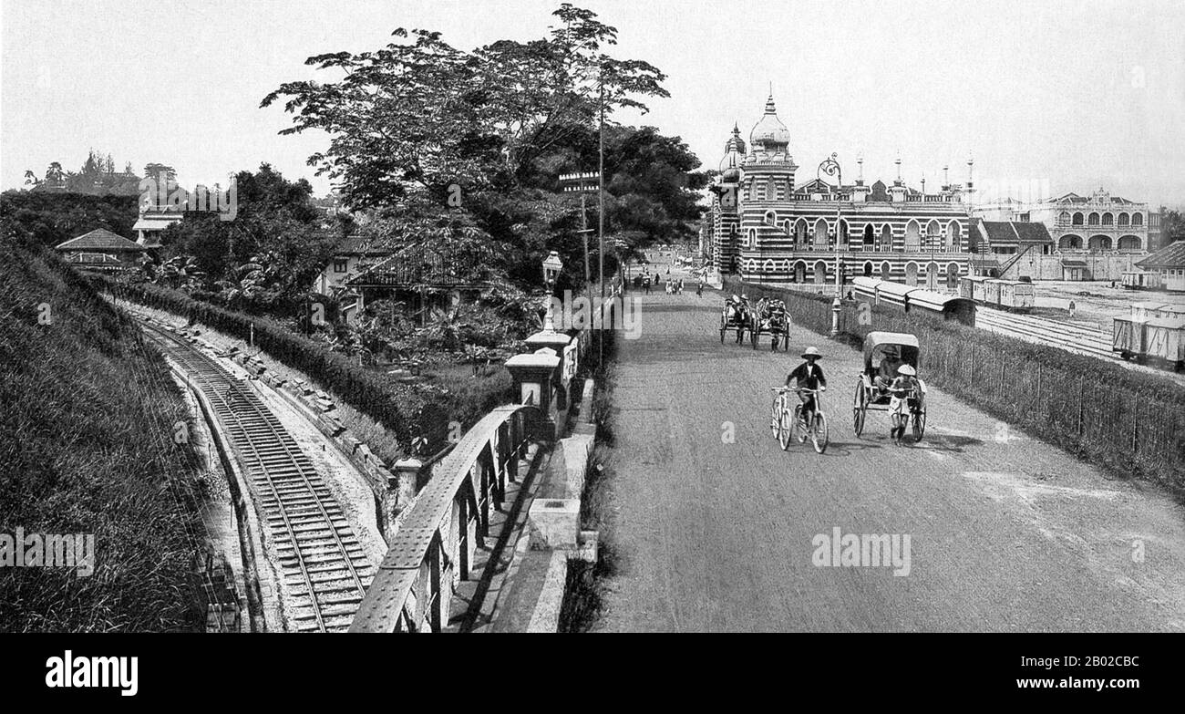 Malesia: Risciò e biciclette attraversano il ponte ferroviario con il vecchio edificio ferroviario FMS sullo sfondo, Kuala Lumpur. Foto di Carl Josef Kleingrothe (1864-1925), c. 1910. Kuala Lumpur, fondata nel 1857, si trova alla confluenza dei fiumi Gombak e Kelang. Il nome significa "foce di fiume fangosa" in malese. L'insediamento iniziò quando Raja Abdullah, un membro della famiglia reale di Selangor, aprì la valle del Klang ai cercatori cinesi. Fu istituita una miniera di stagno, incoraggiando i commercianti a trasferirsi. Foto Stock
