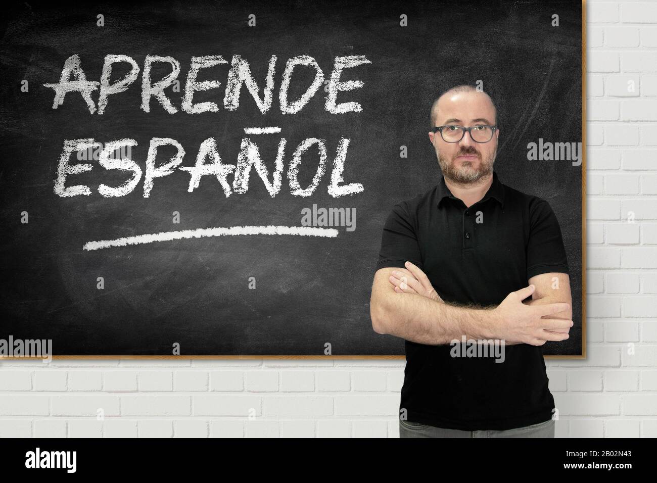Insegnante di spagnolo caucasico che si trova in una classe linguistica. Lavagna con testo scritto a mano in spagnolo. Foto Stock