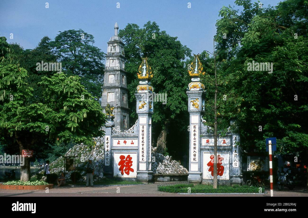 Den Ngoc Son, o ‘Jade Mountain Temple’, è uno dei complessi religiosi più venerati della capitale. Istituito dal mandarino studioso Nguyen Van Sieu (1799–1872) simboli appropriati di apprendimento e letteratura segnano il complesso del tempio. Una lastra di inchiostro stilizzata in pietra poggia in cima alla porta ad arco all'ingresso; nelle vicinanze, un pilastro di pietra affusolato che rappresenta una penna a spazzola cinese tradizionale si erge su cinque livelli. Da parte sua, tre ideogrammi cinesi proclamano ta thanh thien, o ‘scrivere su un cielo limpido’. Oltre l'entrata, un ponte di legno dipinto di rosso, con un arco di grazia conduce attraverso il gre STILL Foto Stock