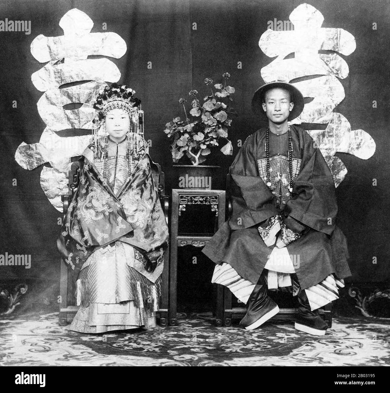 Thomas Child ha scattato una serie di tre fotografie relative alle abitudini di matrimonio della dinastia Qing tardiva. Questa mostra la nipote del generale Zeng Guofan, un alto funzionario Qing, seduto accanto al suo sposo. Il bambino descrive questa fotografia: 'I matrimoni sono una delle cerimonie di stock del mondo e ogni paese ha la sua propria dogana. In Cina il colore nuziale è scarlatto. Questa sposa indossava un cappotto raso scarlatto ricamato con filo d'oro, con una gonna a fiammifero, il suo capo vestito era una massa di scarlatto, oro e perle.'. Foto Stock