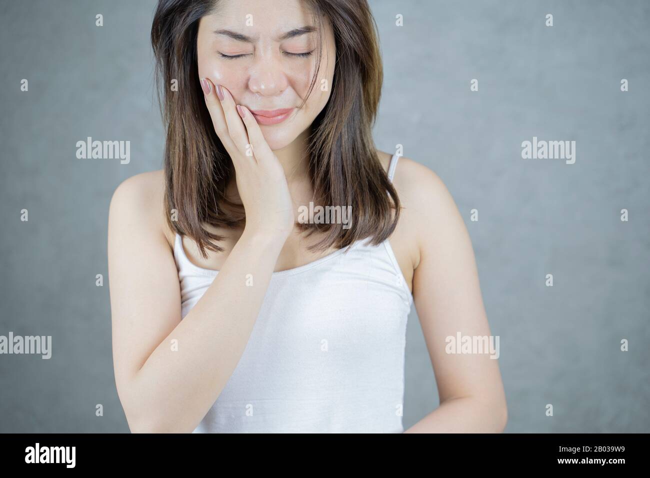 Dolore E Dentista Dei Denti. Giovane Donna Asiatica Che Soffre Di Terribile Forte Dolore Ai Denti, Toccando Guancia Con Mano. Foto Stock