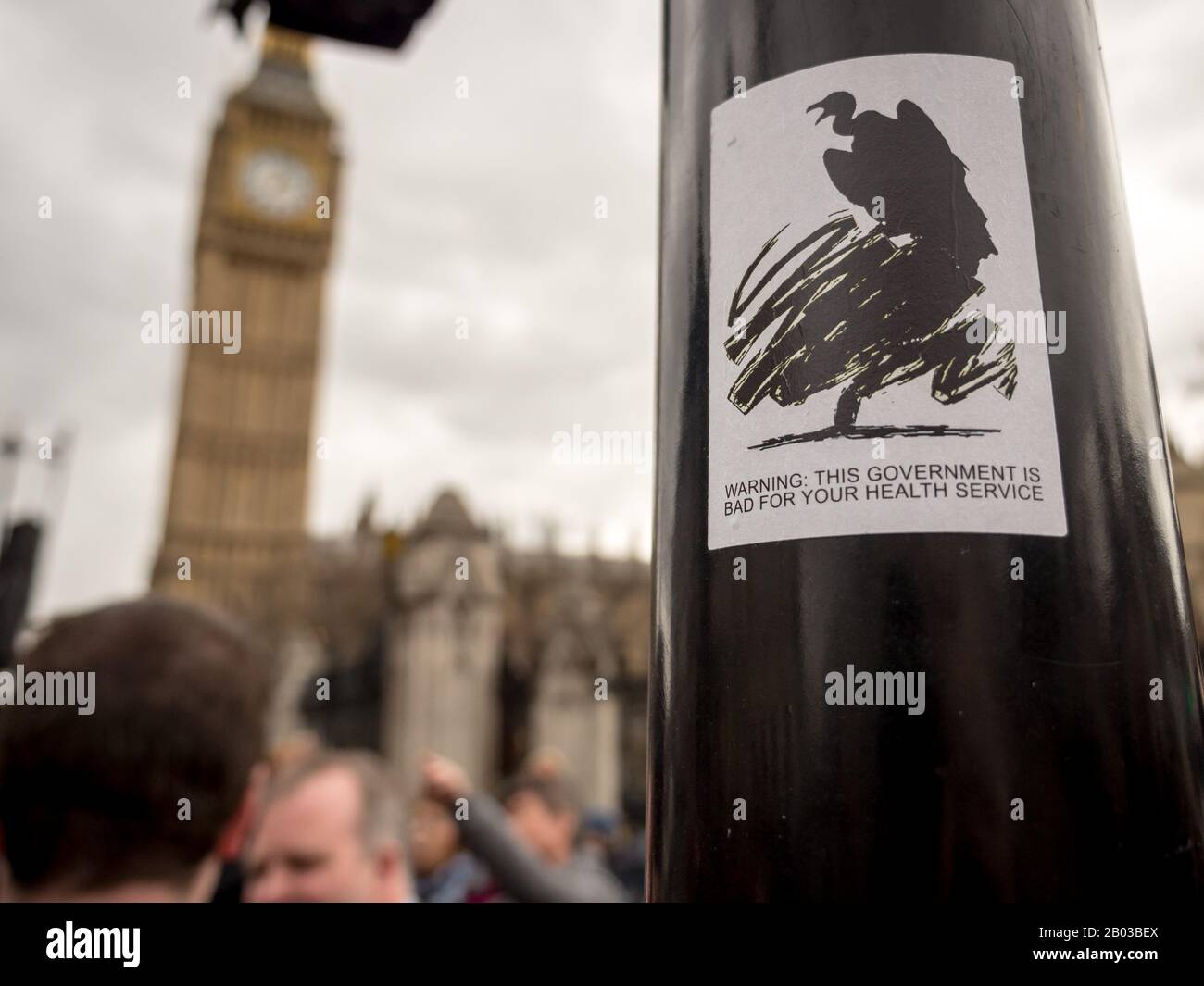 Street art che satirizza le ripercussioni del governo conservatore britannico sul servizio sanitario nazionale con il Big ben in background blur. Foto Stock