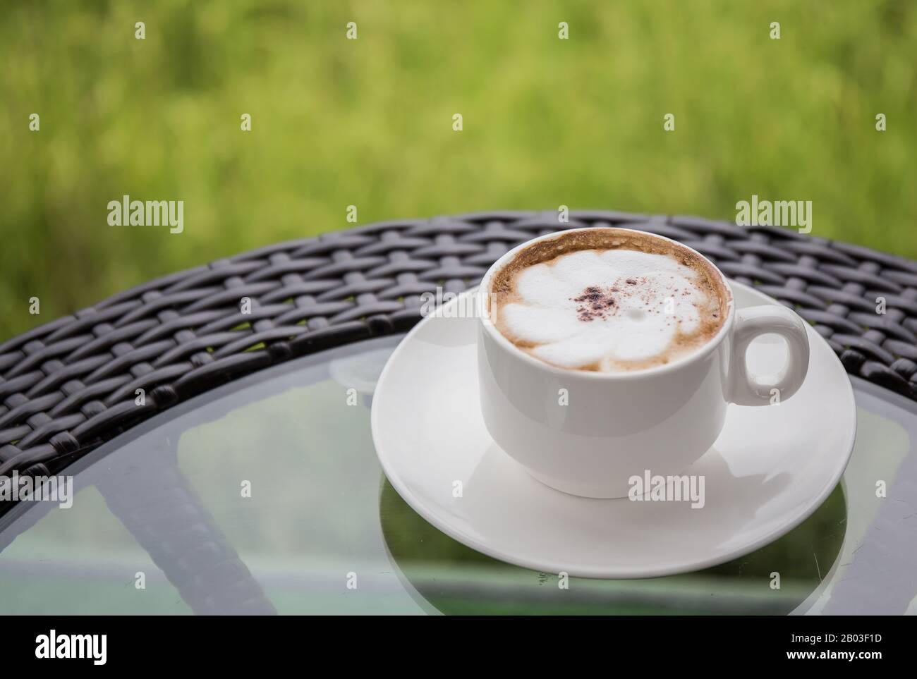 Una tazza bianca di caffè sul tavolo con un sottofondo di risaie. Foto Stock