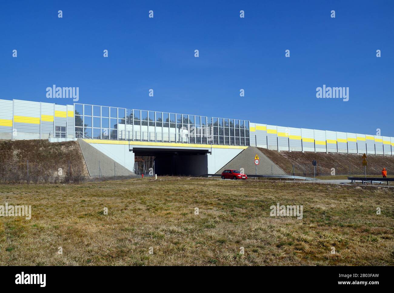 Autostrada circondata da barriere fonoassorbenti. Sotto l'autostrada, un viadotto per la strada locale. Foto Stock