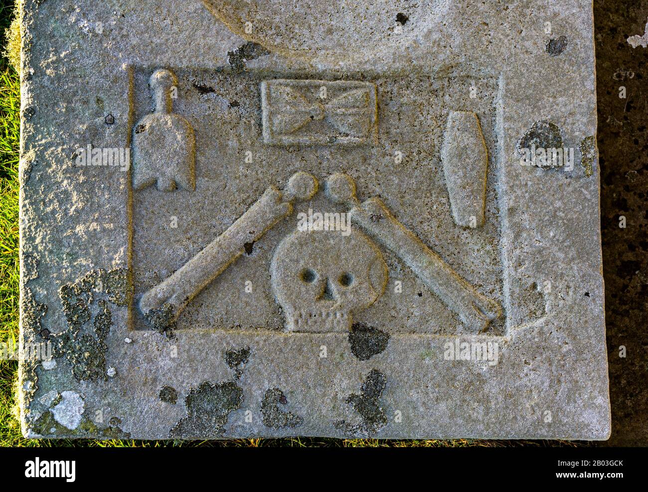 Cranio e ossa scolpite su una lapide alla Cappella di Santa Maria a Crosskirk, vicino a Thurso, Caithness, Scozia, Regno Unito Foto Stock