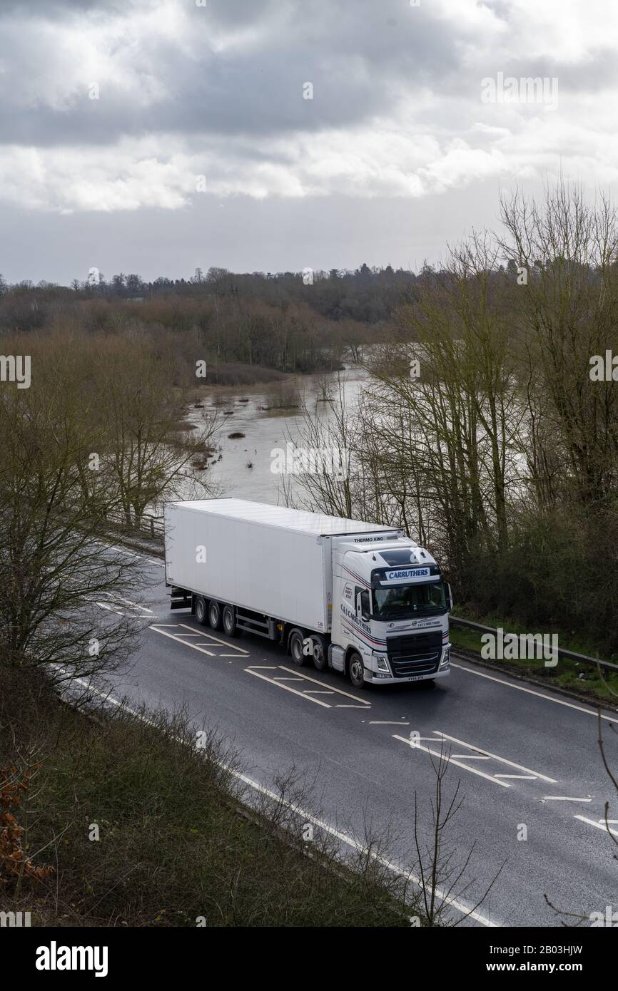 Guardando giù su un bianco HGV viaggiando verso ovest sulla A5 in Shropshire su un fiume inondato Severn che ha scoppiato le sue banche e campi allagati vicino. Foto Stock