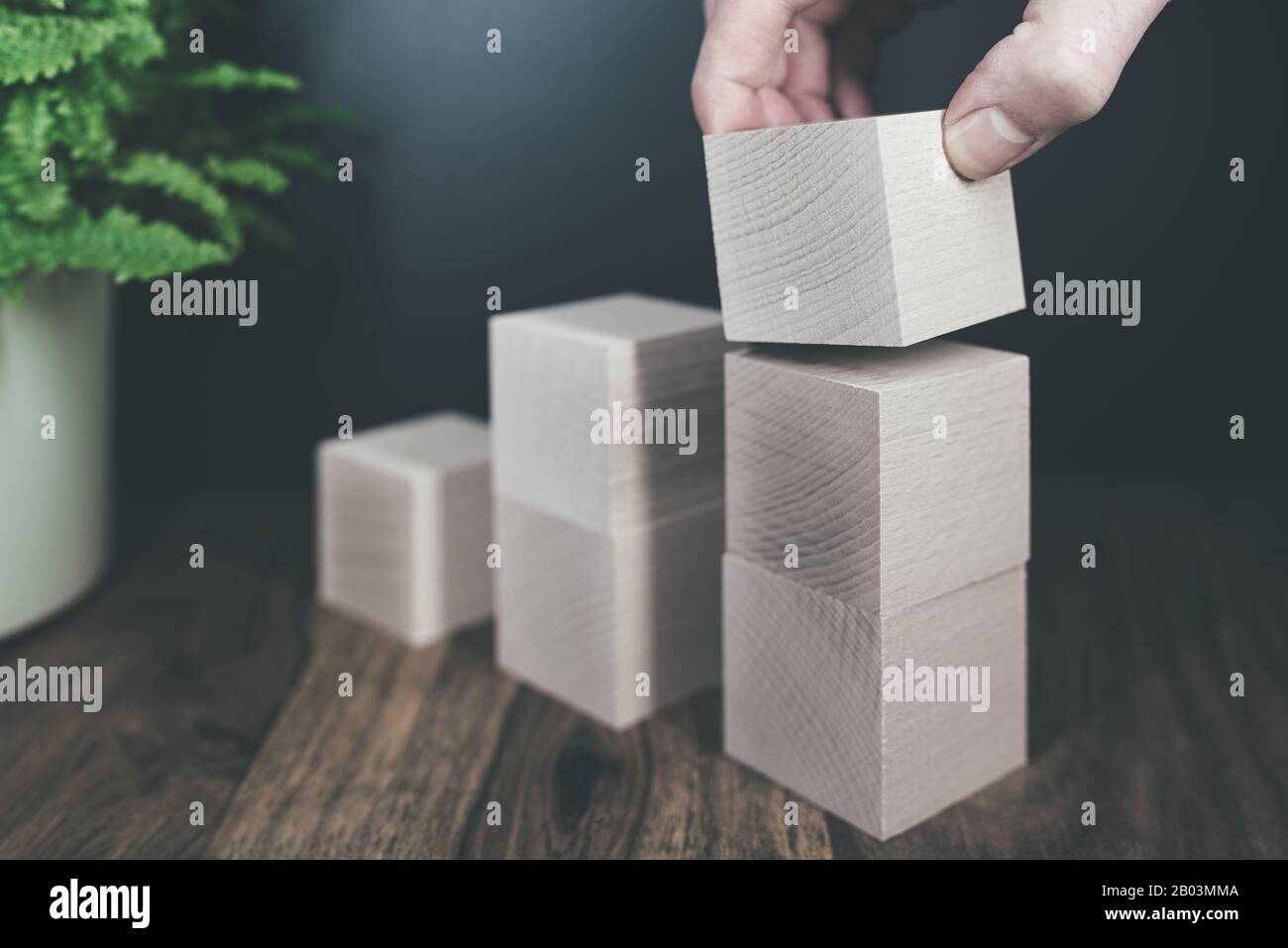 primo piano di mano accatastando blocchi di legno in passi, il business o il concetto di crescita economica Foto Stock