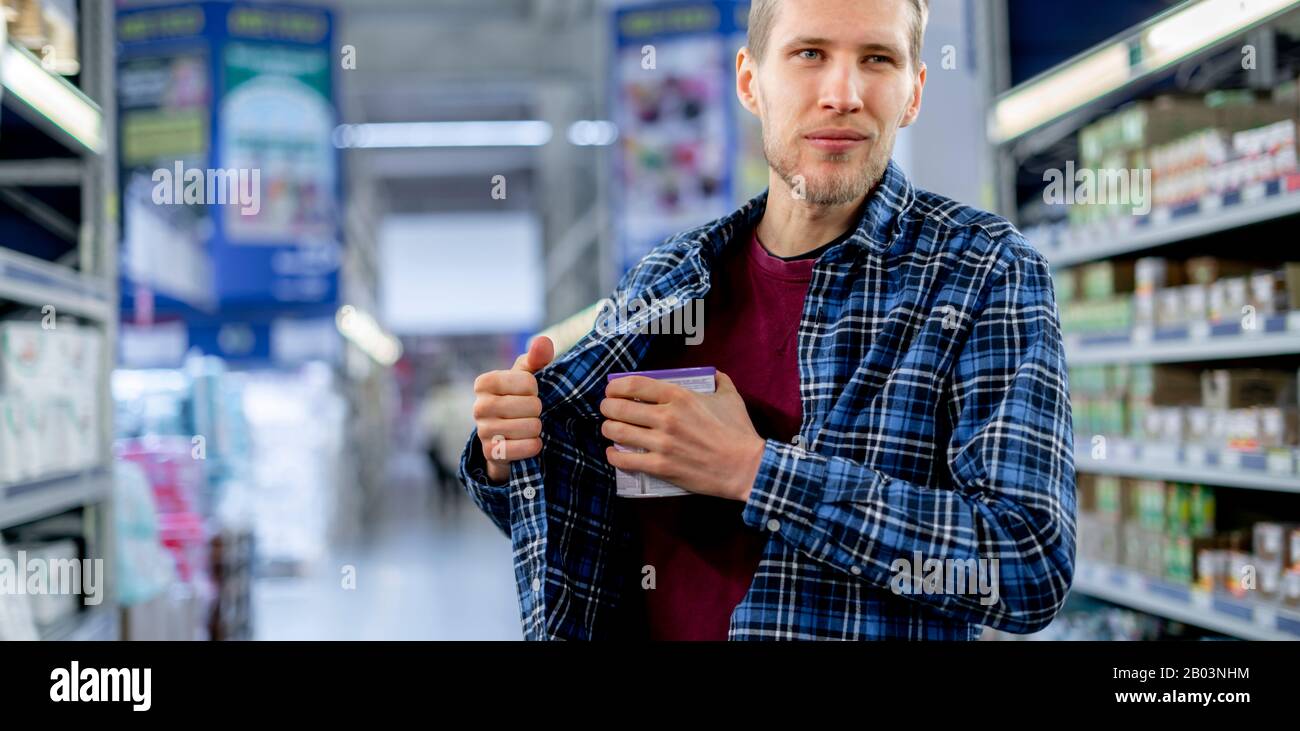 kleptomania concetto, un uomo nel negozio di alimentari rubare cibo e metterlo in tasca Foto Stock