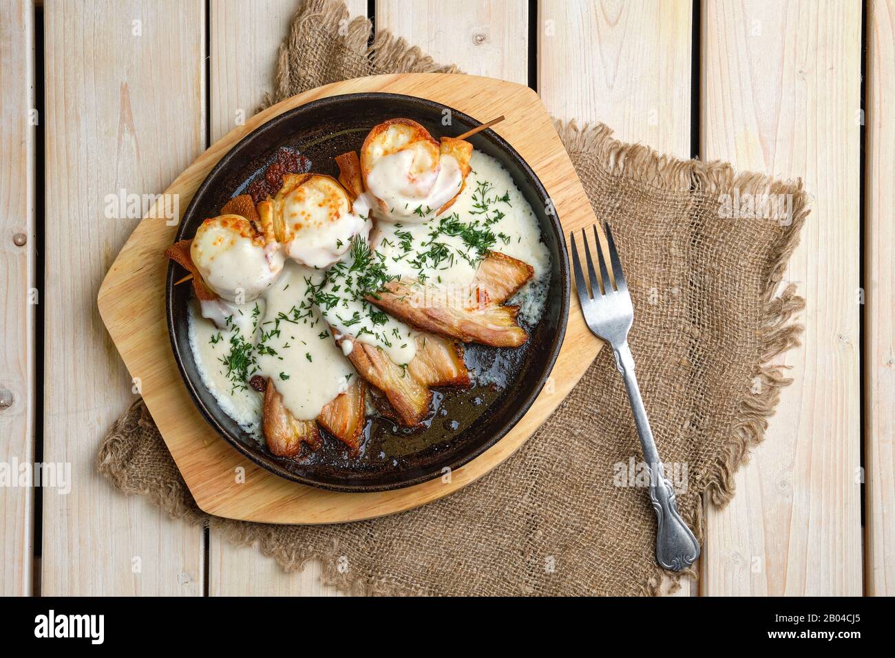 Vista dall'alto di frittelle sottili su spiedini farciti con formaggio e serviti con pancetta fritta Foto Stock