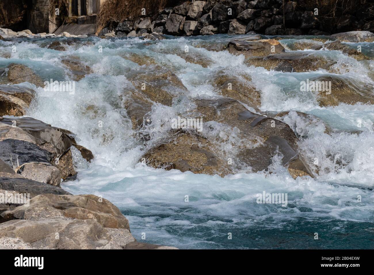 Onde di un fiume di montagna che si infrangono nel forte ruscello contro le pietre e i massi della cascata Foto Stock