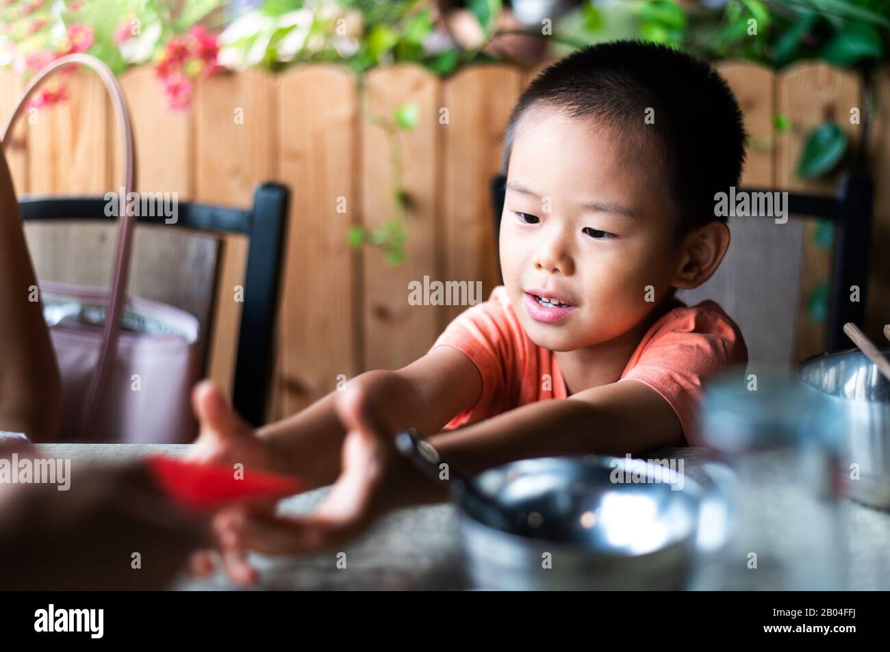 Bambino cinese che riceve tasca rossa sul tavolo da pranzo Foto Stock