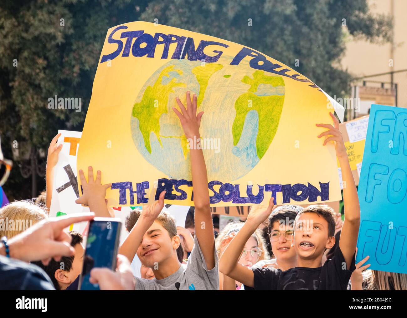 Un gruppo di giovani ragazzi ha un segnale con un messaggio e un disegno per protestare contro il cambiamento climatico. Foto Stock