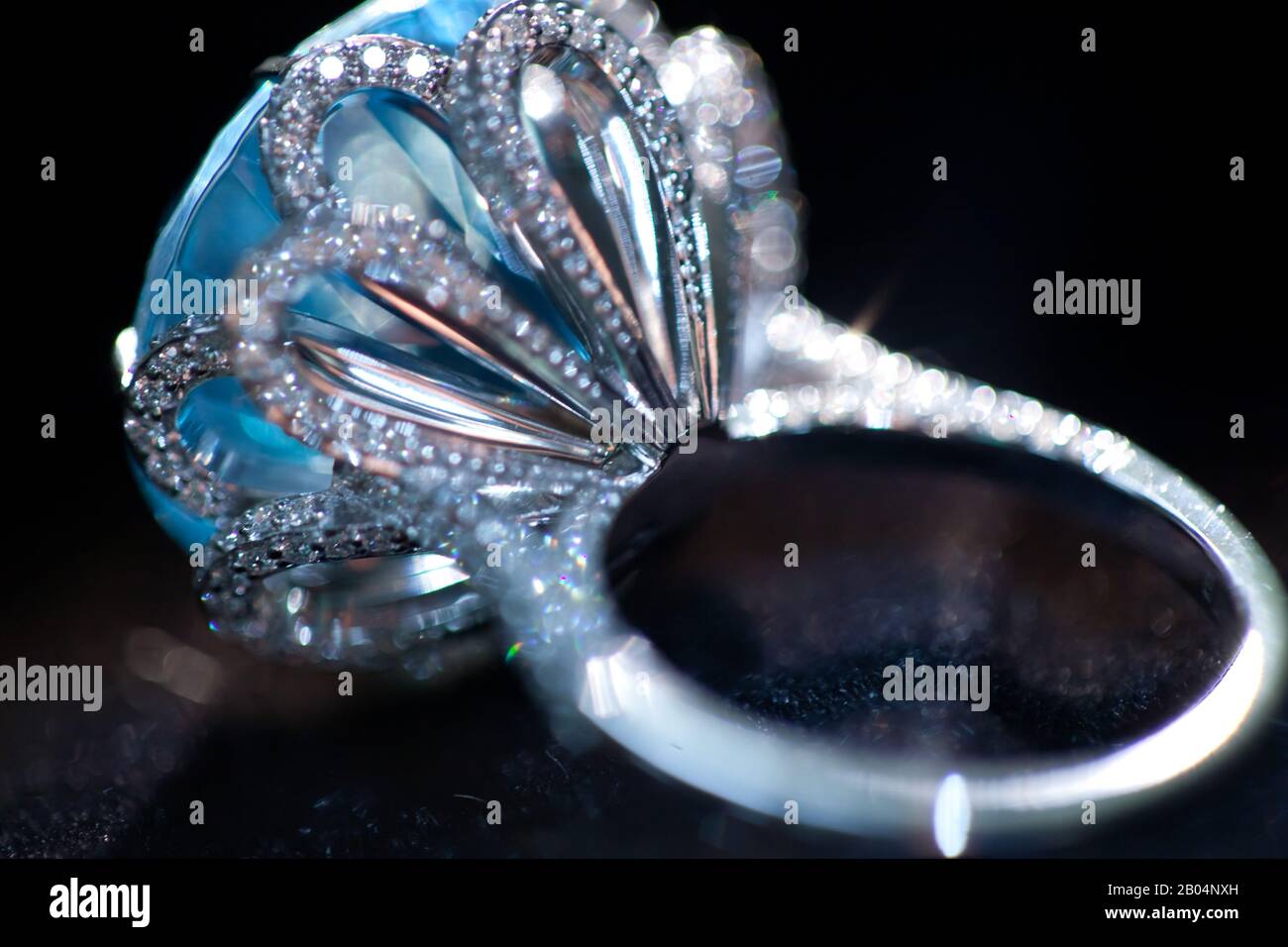 macro scatto di un anello bianco di metallo prezioso con grande gemma blu, su sfondo nero Foto Stock