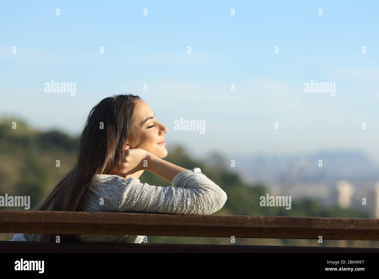 Vista laterale ritratto di donna rilassante sollievo stress seduta su una panchina nella periferia della città Foto Stock