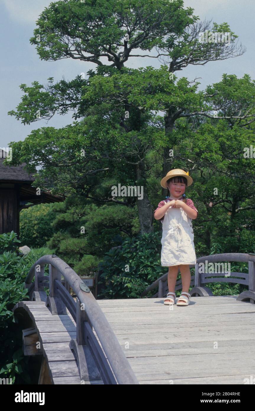 Una ragazza giapponese su un ponte nel Korakuen Garden giapponese situato a Okayama in Giappone. Foto Stock