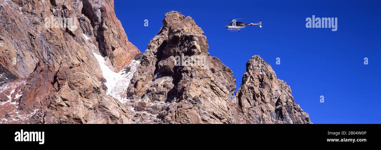 Vista ad angolo basso di un elicottero che vola sulle montagne, Grand Teton National Park, Wyoming, USA Foto Stock