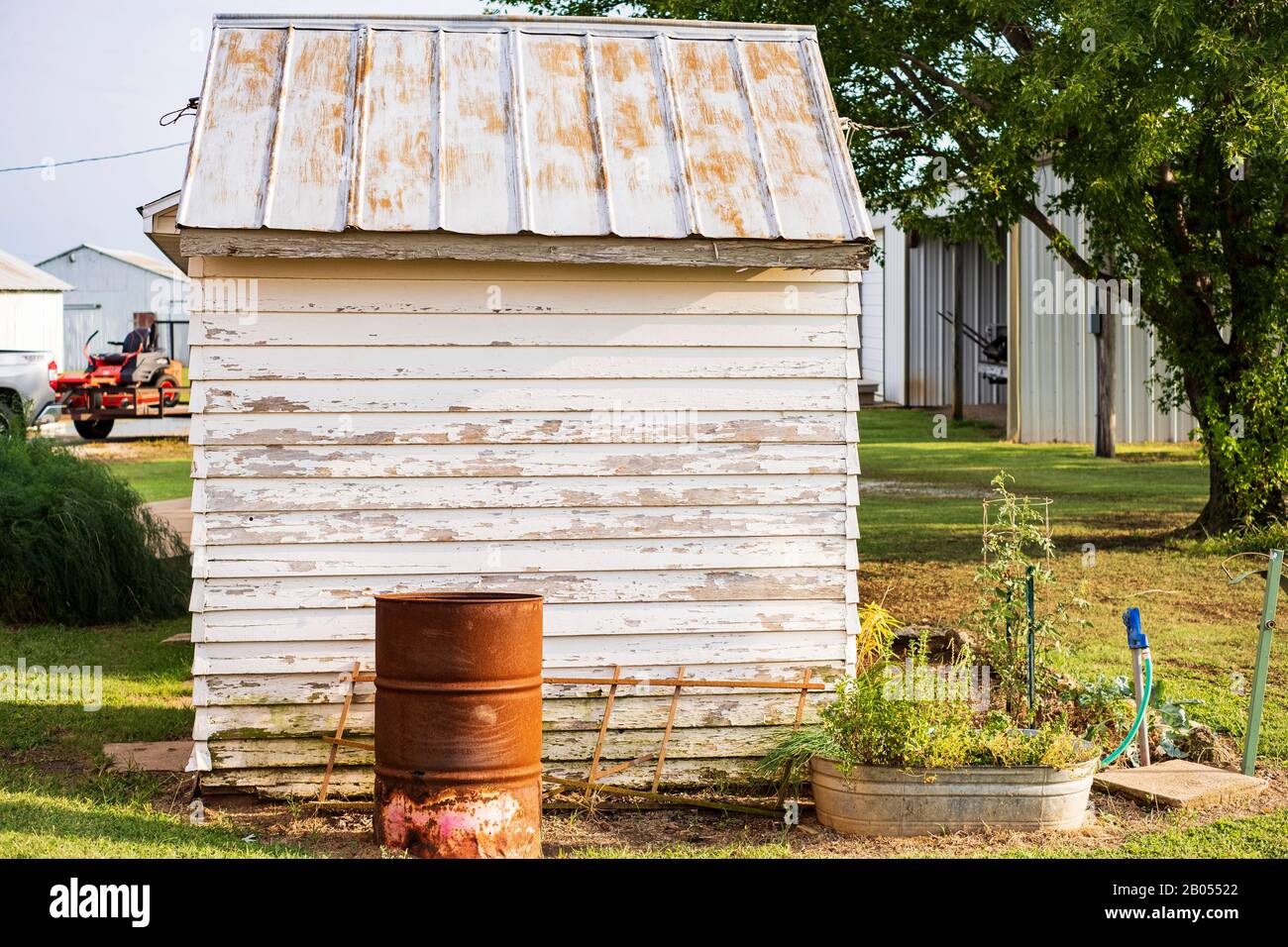 Un cortile dell'Oklahoma che mostra un edificio in legno peeling con un tetto in stagno arrugginoso e altri annessi. Oklahoma, Stati Uniti. Foto Stock