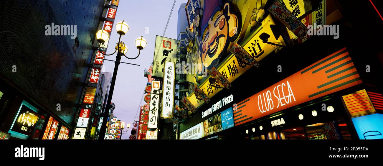Vista ad angolo basso degli edifici illuminati lungo un canale, Dotonbori, Osaka, Prefettura di Osaka, regione di Kinki, Honshu, Giappone Foto Stock