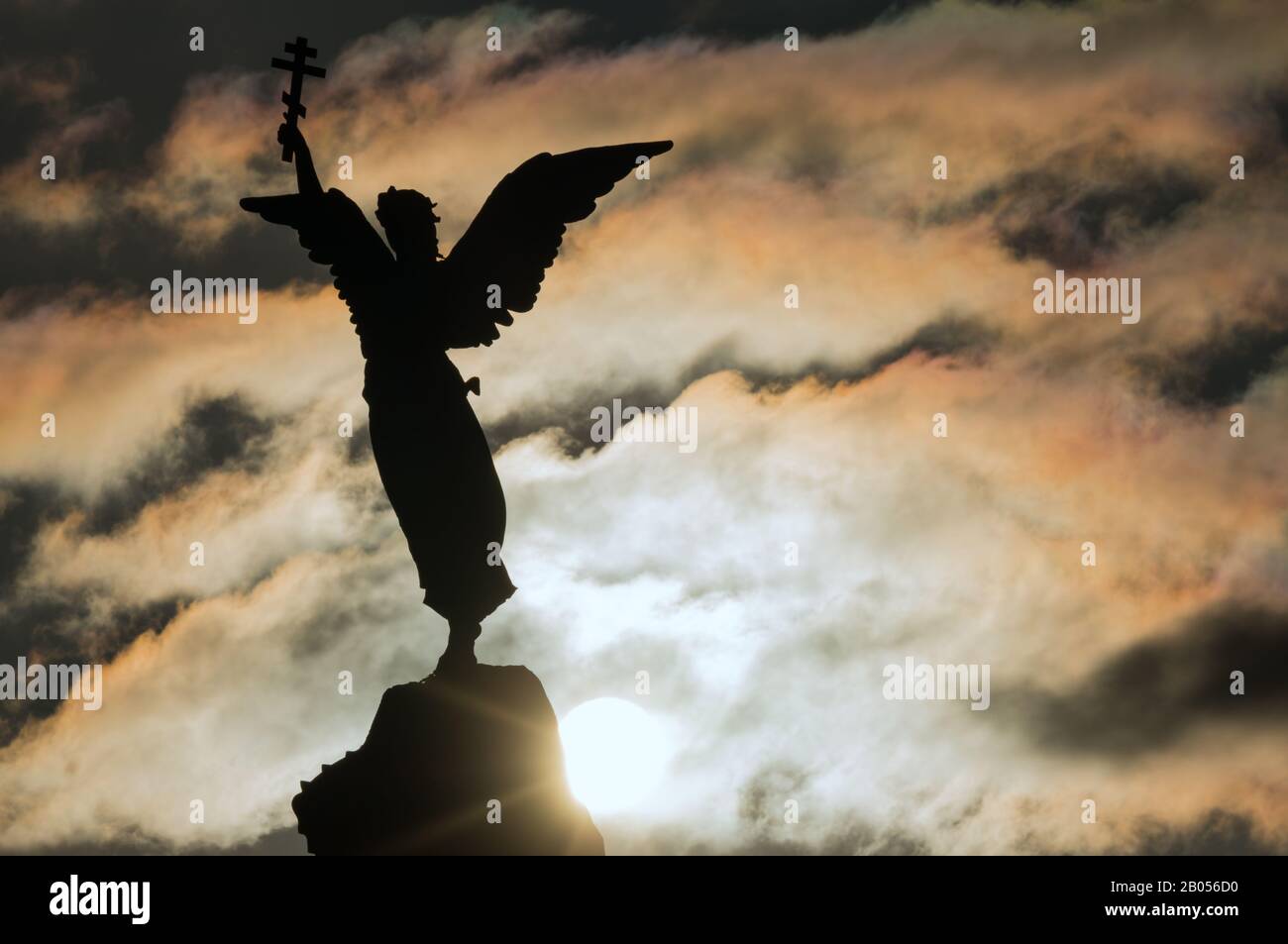 Tallinn, Estonia - 01.05.2020: Silhouette di un angelo con una croce in mano su uno sfondo di cielo e sole drammatico. Frammento del Monumento Merma Foto Stock