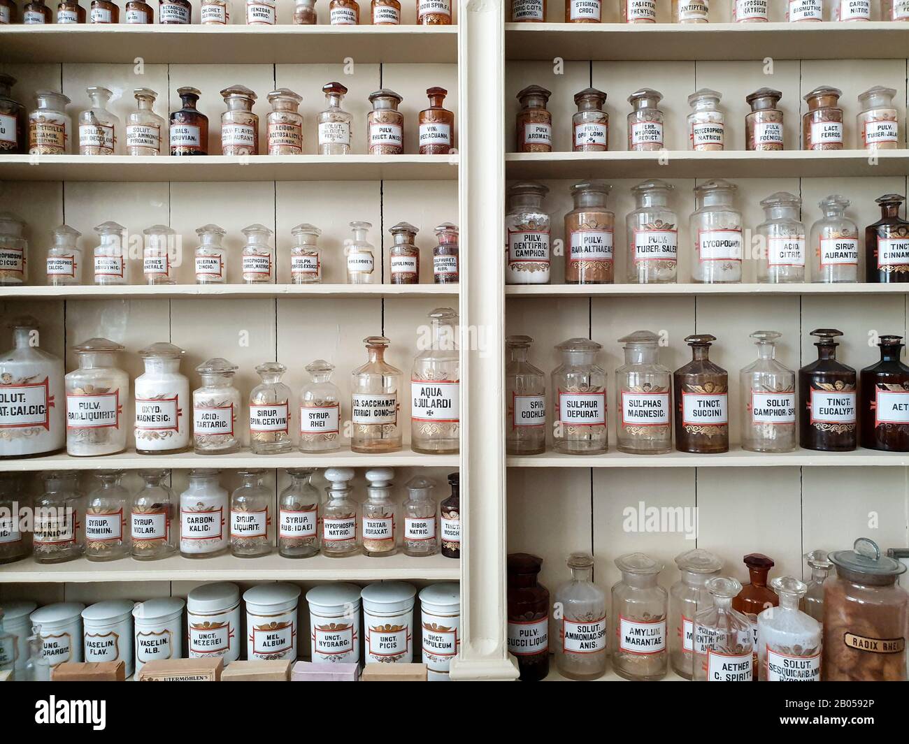 Un primo piano degli scaffali in una vecchia farmacia, bottiglie in vetro con etichetta latina riempite di sostanze chimiche per la preparazione della medicina. Foto Stock