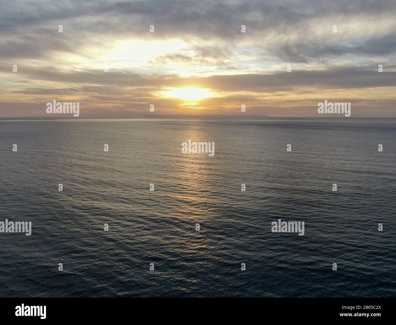 Vista aerea del tramonto colorato dell'oceano Pacifico, di fronte al sole con riflessione sull'oceano e cielo profondo e nuvoloso. Newport Beach, California Foto Stock