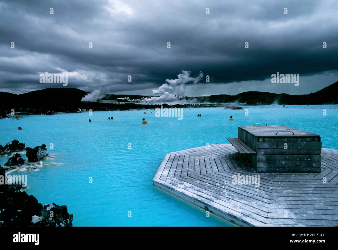ISLANDA, VICINO REYKJAVIK, BLU LAGUNA ZONA TERMALE, SPA, PERSONE IN PISCINA, CENTRALE ELETTRICA IN BACKGROUND Foto Stock