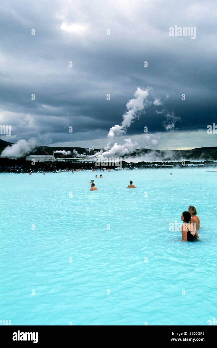 ISLANDA, VICINO REYKJAVIK, BLU LAGUNA ZONA TERMALE, SPA, PERSONE IN PISCINA, CENTRALE ELETTRICA IN BACKGROUND Foto Stock
