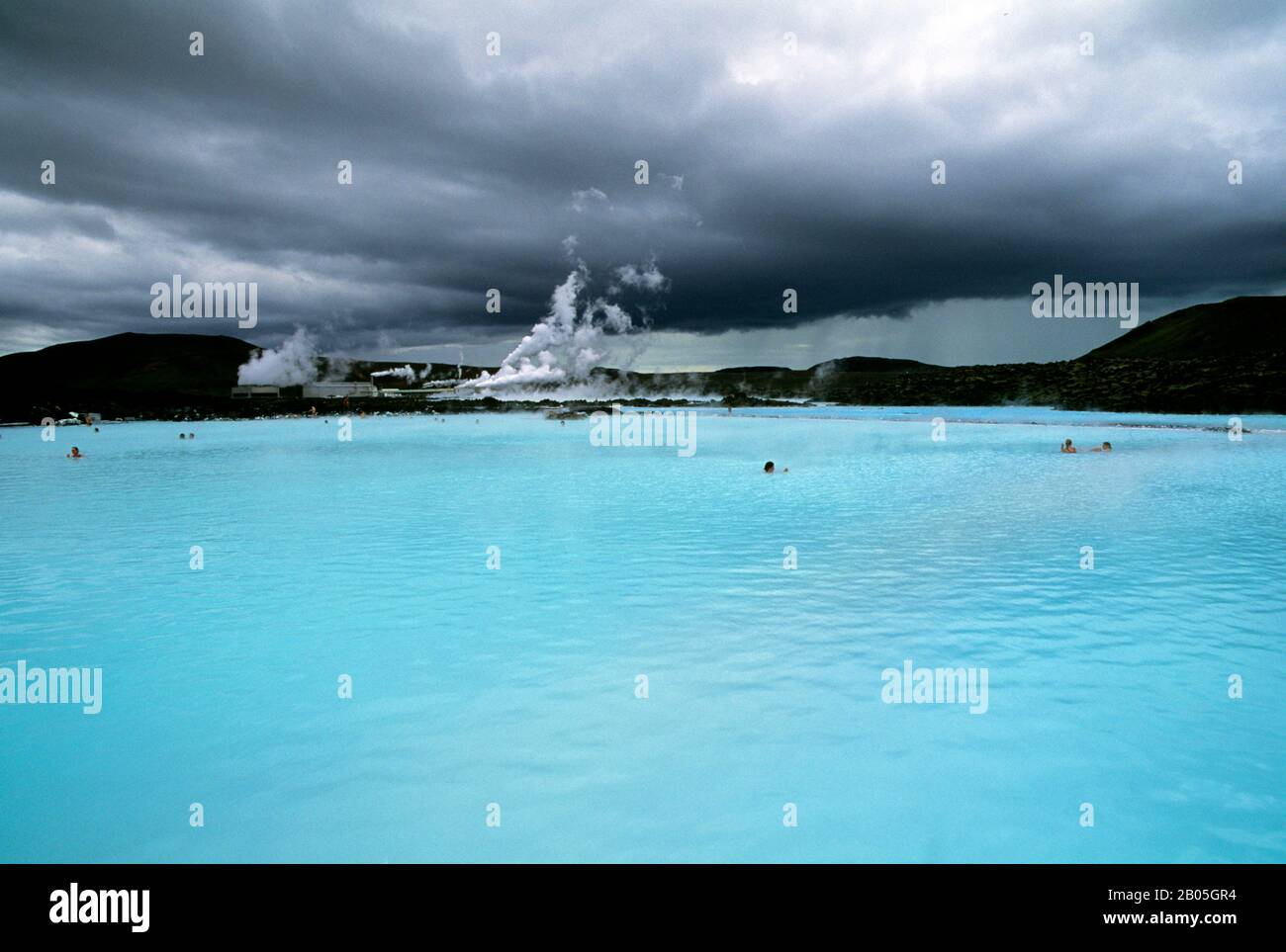 ISLANDA, VICINO REYKJAVIK, BLU LAGUNA ZONA TERMALE, SPA, PERSONE IN PISCINA, CENTRALE ELETTRICA IN BACKGROUND Foto Stock