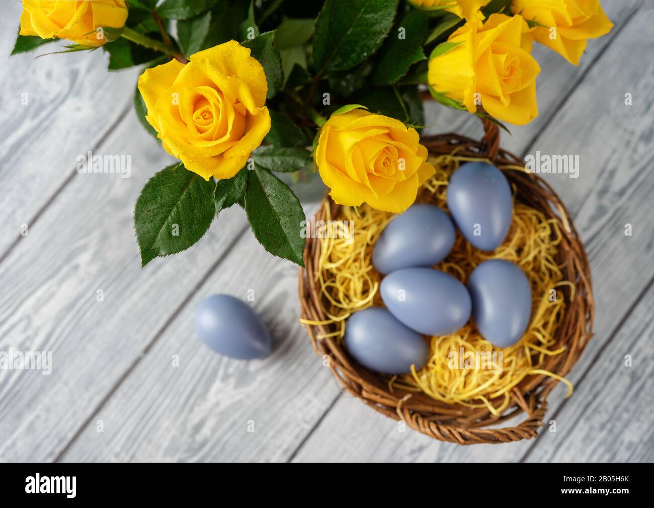 Uova di Pasqua in cestino e rose gialle vedere dall'alto Foto Stock