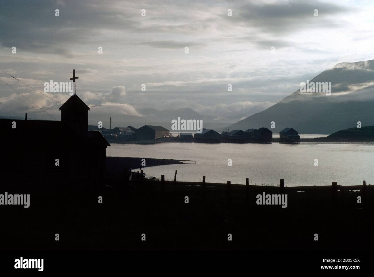 USA, ALASKA, KODIAK ISLAND LARSEN BAY, CHIESA SILHOUETTE CON SFONDO CANNERY, LUCE SERALE Foto Stock
