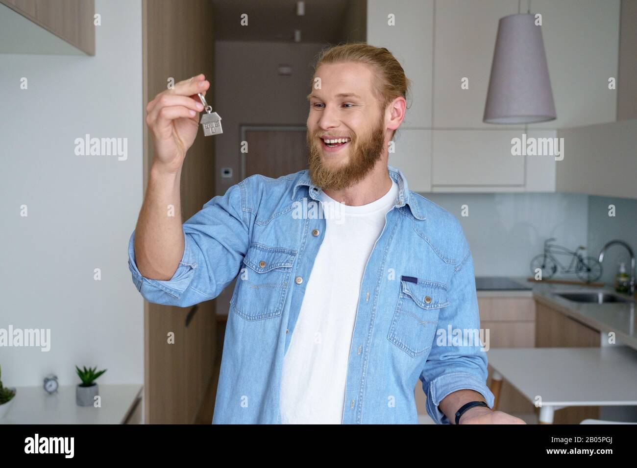 Felice giovane uomo rentire prima volta proprietario di casa tenendo la chiave per nuovo appartamento Foto Stock