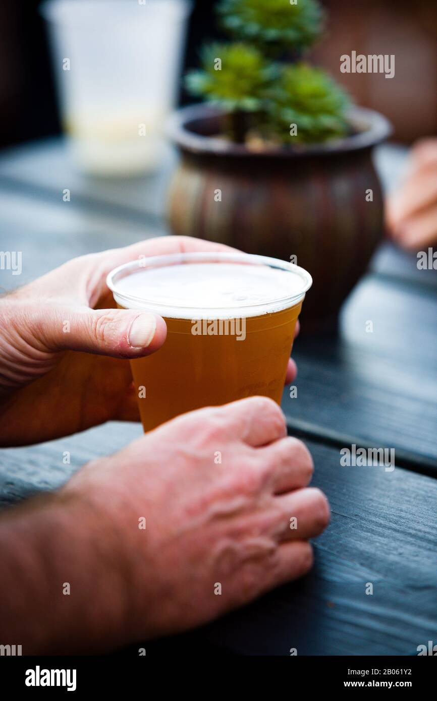 Mani che bevono una birra su un tavolo di legno Foto Stock